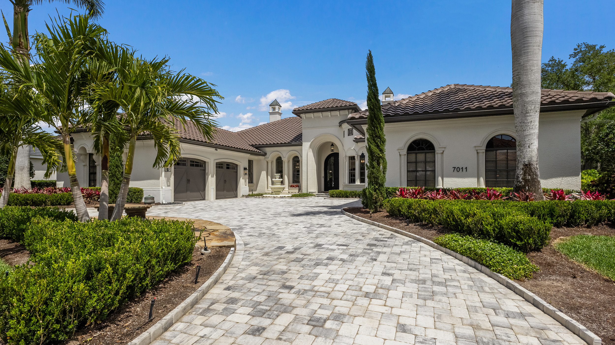 The home's exterior features classic Palladian architecture, with a new paver driveway and barrel roof.