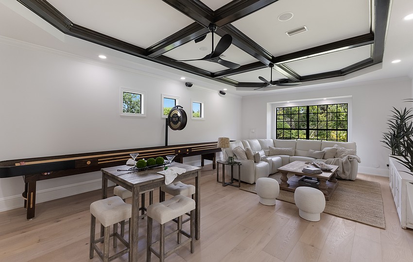 The possibilities of the home’s expansive bonus room are endless. It opens to the outdoor living area, adding extra space for games and recreation. That’s a shuffleboard game table against the rear wall.