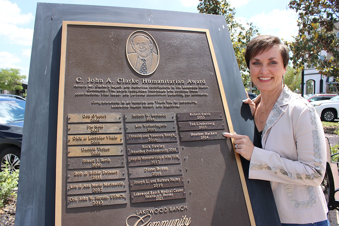 Heather Hackett, the founder of Local Relief, Inc., points to the slat that bears her name as the 2024 C. John A. Clarke Humanitarian Award recipient.